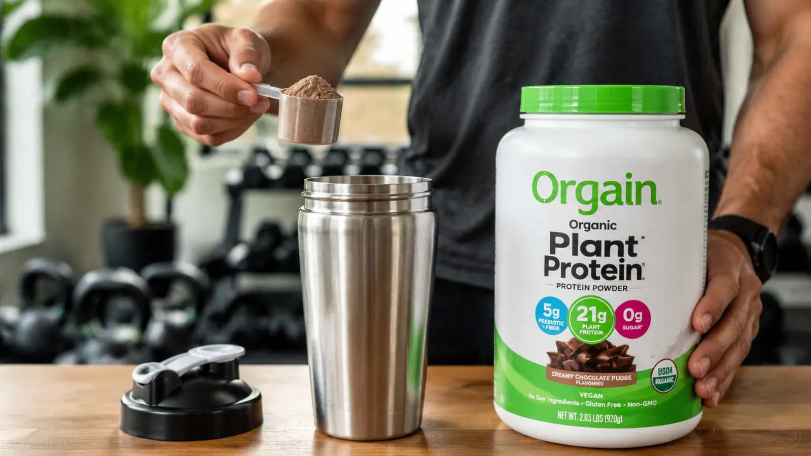 Hand scooping Orgain plant protein powder into a shaker bottle after a home gym workout
