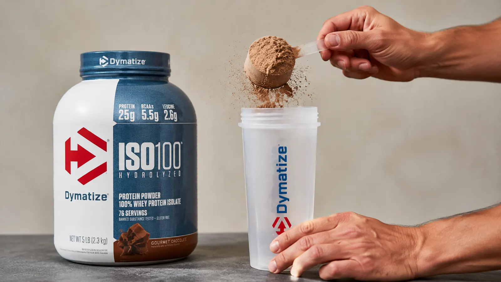 A scoop of ISO100 chocolate protein powder being added to a shaker bottle filled with water