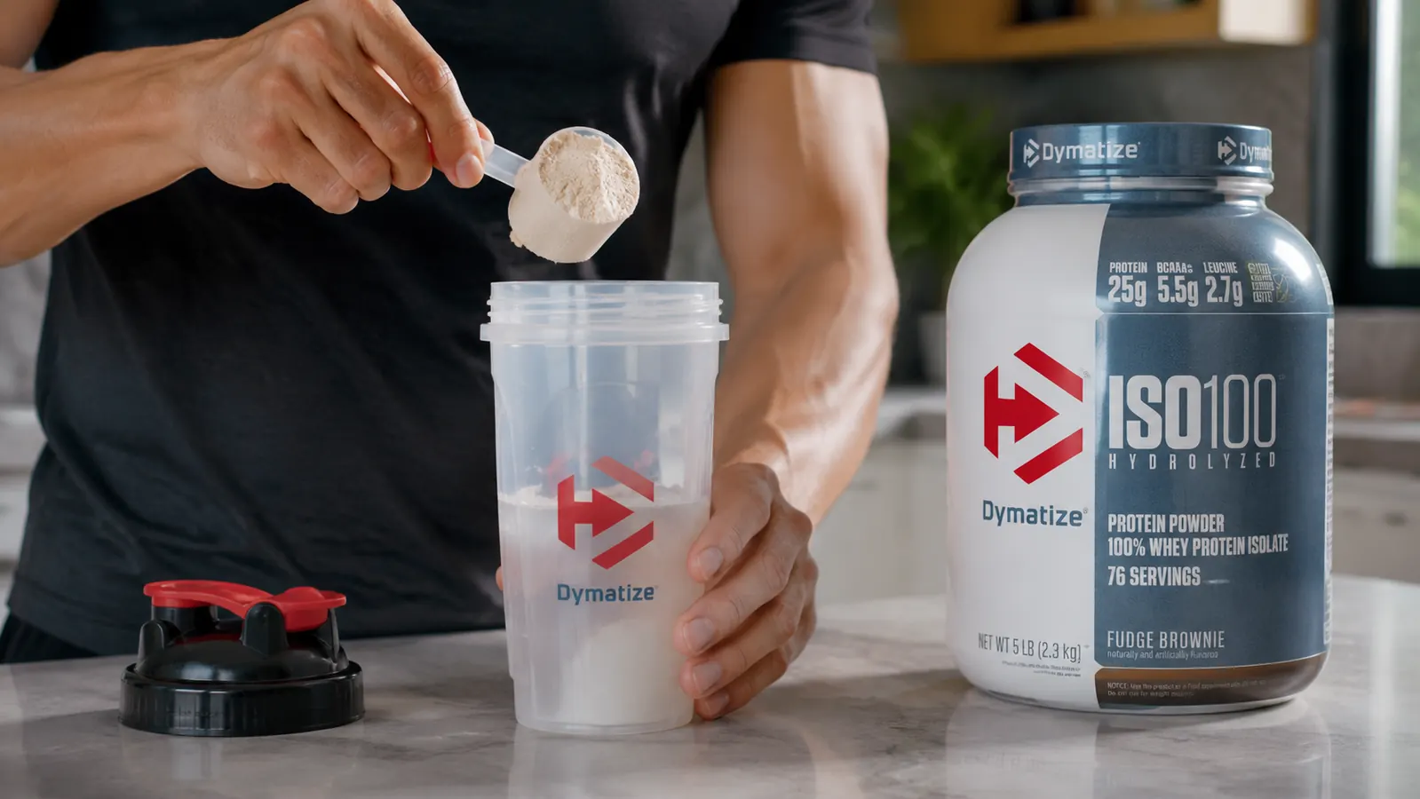 Close-up of a hand scooping Dymatize ISO100 protein powder into a shaker bottle