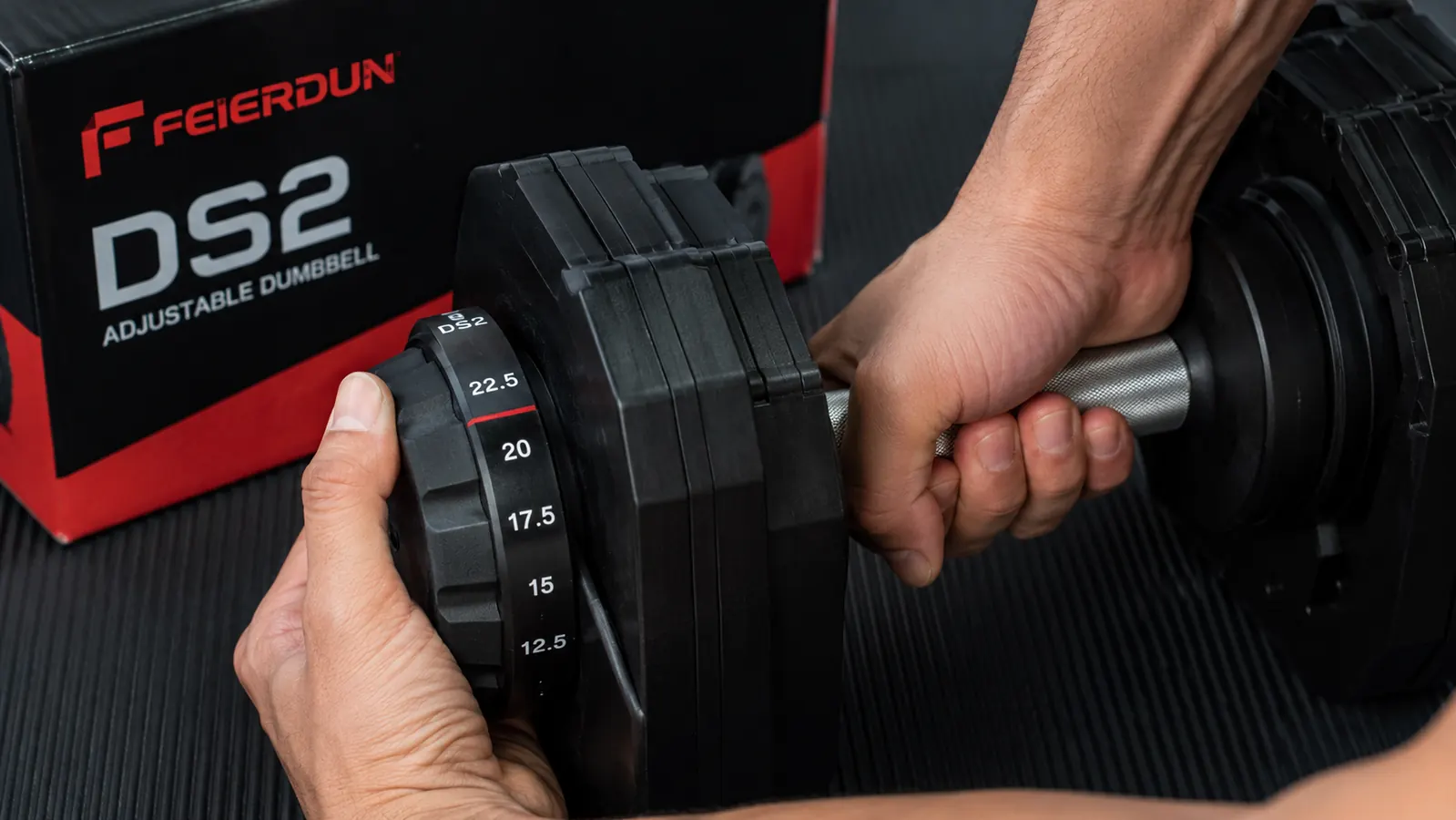 Hand gripping the FEIERDUN DS2 adjustable dumbbell handle, selector dial visible