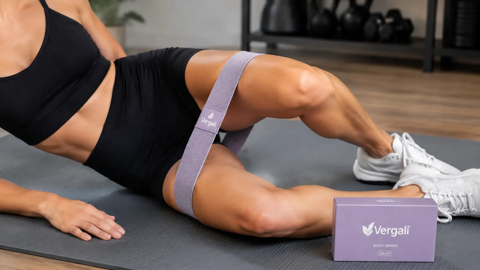 Close-up of Vergali resistance bands looped around knees during a clamshell exercise on a yoga mat