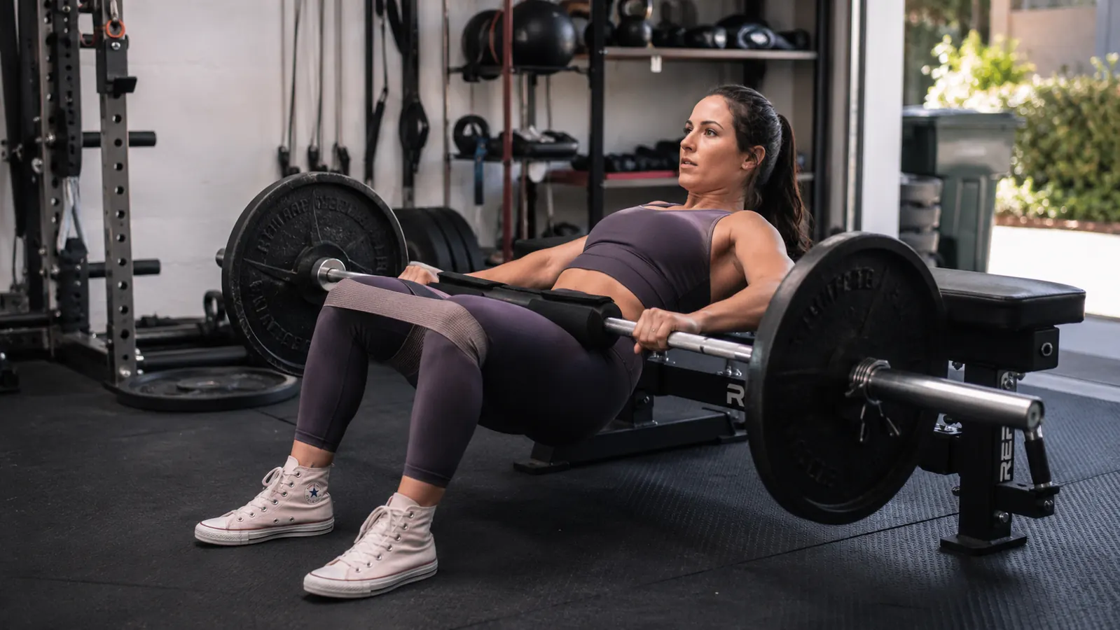 Woman doing a hip thrust with a resistance band looped around her hips on a bench